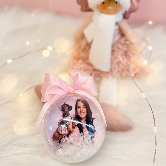 Adorno navideño personalizado con foto de persona y su mascota, bola transparente con lazo rosa y nieve decorativa de Sweet Gift.